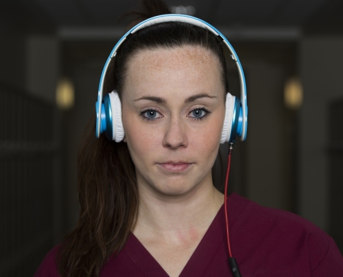 Jeune femme en blouse d'infirmière avec casque sur les oreilles