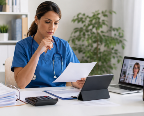 Infirmière libérale comparant sa facturation médicale sur ordinateur avec documents administratifs